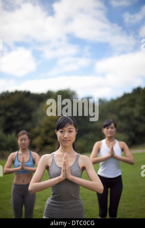 Three young women in park practicing yoga Stock Photo
