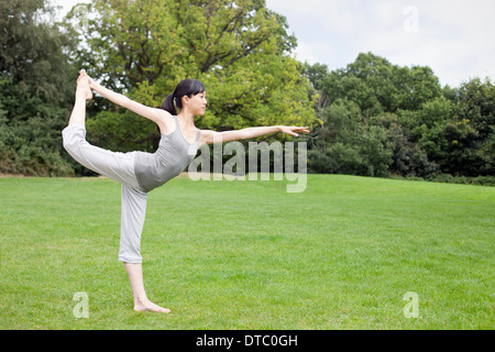 Young woman in park practicing yoga king dancer pose Stock Photo