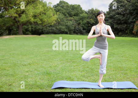 Young woman in park practicing yoga tree pose Stock Photo