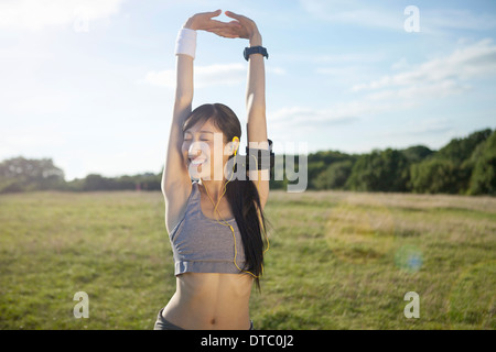 Young female runner stretching arms and warming up