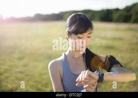 Young female runner checking watch for time