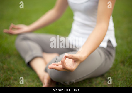 Cropped image of young woman in park practicing lotus position Stock Photo
