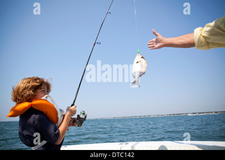 Boy reeling in fish on boat, Falmouth, Massachusetts, USA Stock Photo