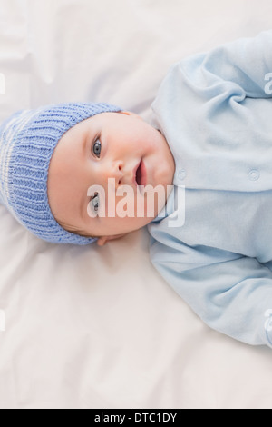 Innocent baby wearing knit hat in bed Stock Photo