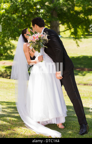 Romantic newlywed couple kissing in park Stock Photo