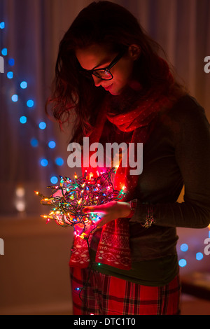 Young woman holding tangle of christmas lights