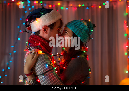 Romantic young couple wrapped in decorative lights at christmas Stock Photo