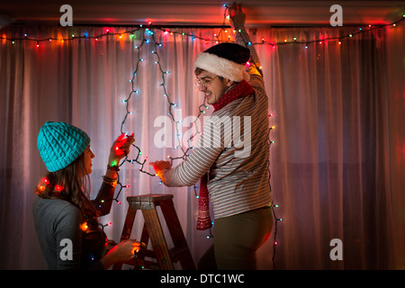 Young couple putting up fairy lights at christmas Stock Photo