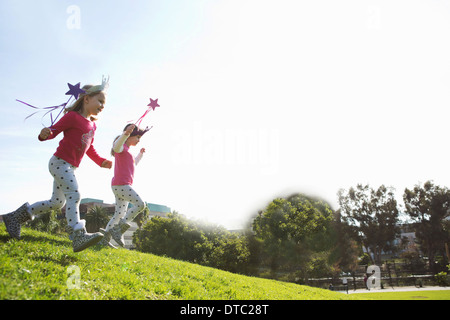Two young sisters dressed up as fairies running down hill Stock Photo