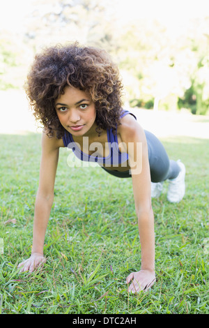 Determined woman doing push ups in park Stock Photo