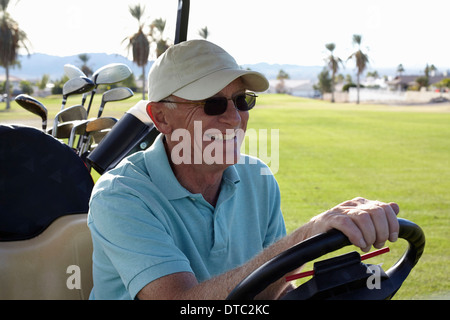 Senior male golfer driving golf buggy Stock Photo