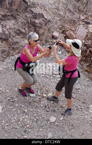 Two senior female hikers photographing each other