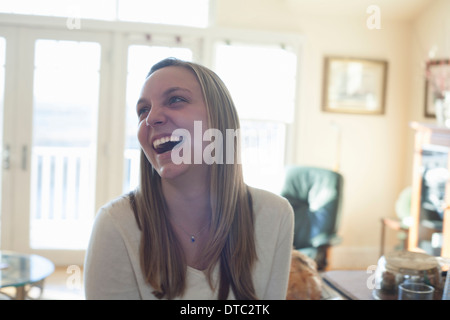 Young woman laughing in sunlit sitting room Stock Photo