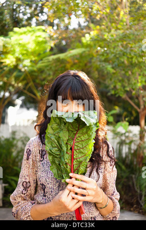 Portrait of young woman holding vegetable leaf Stock Photo