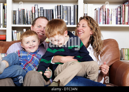 Mid adult parents and young sons sitting on sofa Stock Photo