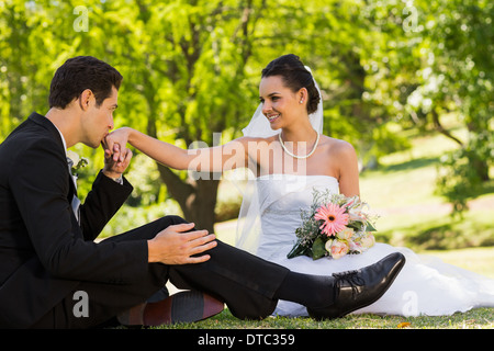 Groom kissing his bride's hand at park Stock Photo