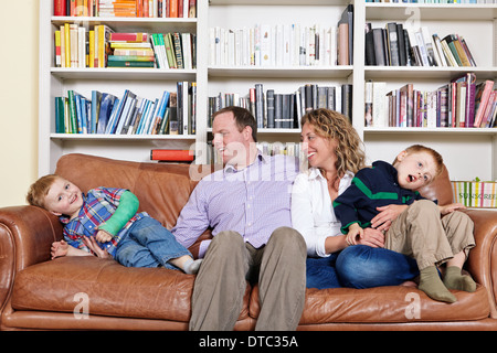 Mid adult parents and young sons having fun on sofa Stock Photo