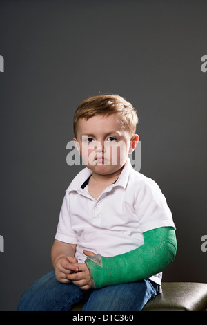 Portrait of sullen young boy with plaster cast on arm Stock Photo