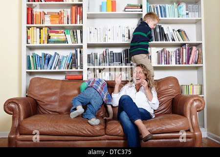 Mother and young sons playing on sofa Stock Photo