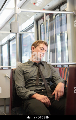 Mid adult office worker snoozing on train journey Stock Photo