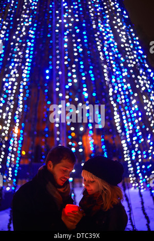 Young couple holding candle in front of city xmas lights Stock Photo