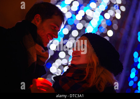 Young couple holding candle in front of city xmas lights
