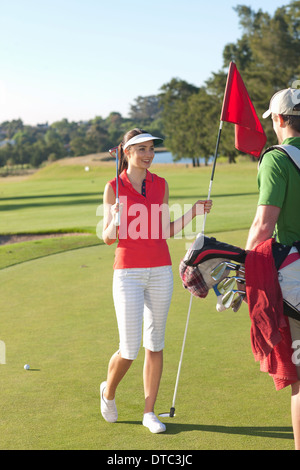 Young female golfer on golf course with caddy Stock Photo