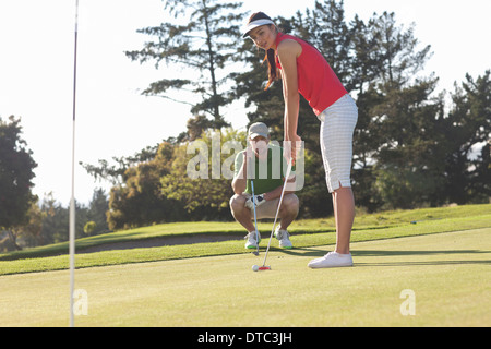 Young female golfer on golf course with trainer Stock Photo