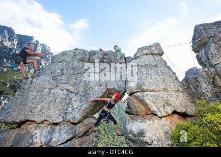 Three rock climbers climbing up rock formation