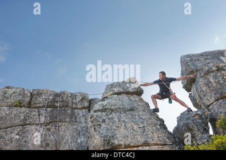 Young man stepping and reaching on rock climb Stock Photo