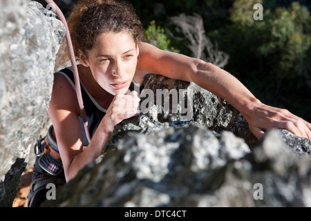 Young female rock climber moving up rock face Stock Photo