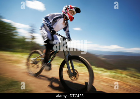 Female mountain biker speeding down dirt track Stock Photo