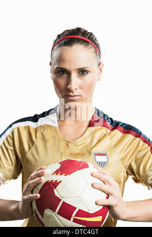 Studio portrait of young female soccer player holding ball Stock Photo