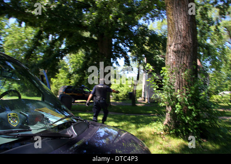 A Detroit police narcotics officer moves carefully towards a house with his gun drawn during a raid. Stock Photo