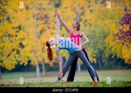 Yoga instructor teaching young woman in forest Stock Photo