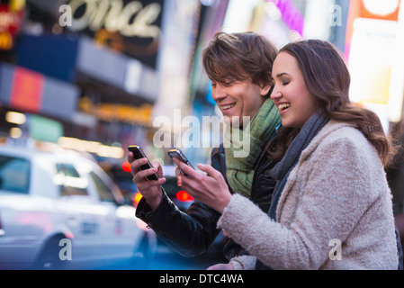 Young couple competing on cell phones, New York City, USA Stock Photo