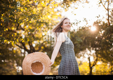 Teenage girl holding sunhat running in park Stock Photo