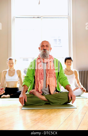 Mature man in lotus pose in yoga class Stock Photo