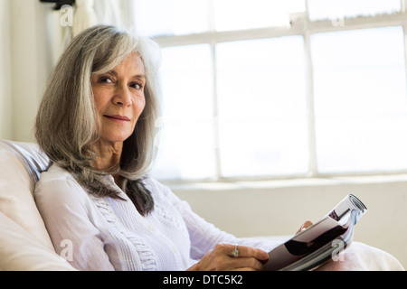 Portrait of attractive senior woman reading magazine Stock Photo