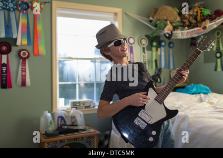 Boy playing guitar in bedroom Stock Photo