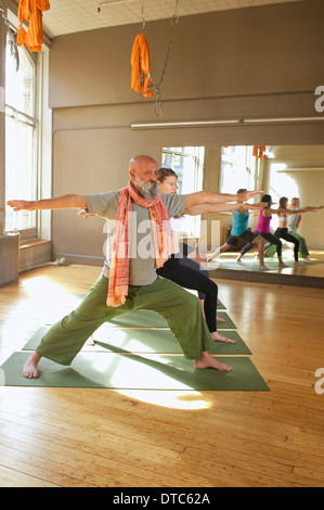 People doing warrior pose in yoga class Stock Photo