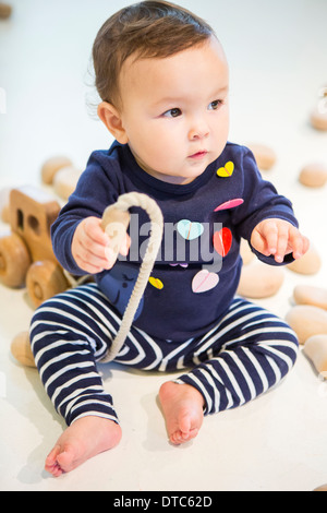 Baby girl sitting on floor with toy Stock Photo