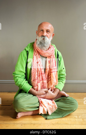 Portrait of mature man sitting in lotus pose on floor Stock Photo