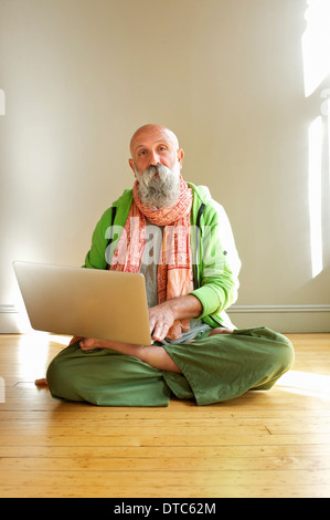 Senior man using laptop in lotus position Stock Photo