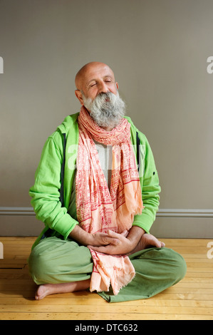 Portrait of senior man sitting in lotus position on floor Stock Photo