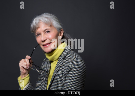 Studio portrait of wise senior woman holding spectacles Stock Photo