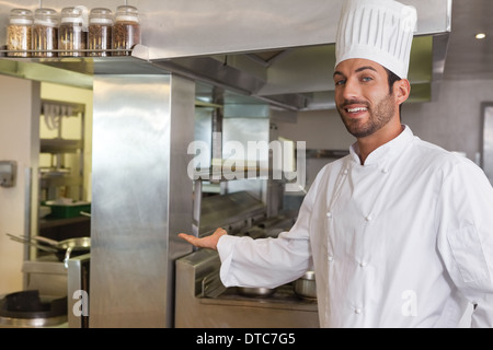 Smiling young chef looking at camera showing his workplace Stock Photo