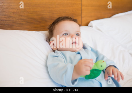 Baby holding toy in bed Stock Photo