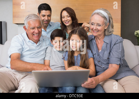 Extended family using laptop on sofa in living room Stock Photo