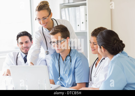 Smiling doctors and nurses discussing over laptop Stock Photo